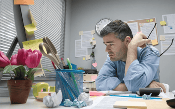 Office worker stares at work he hasn't finished 
