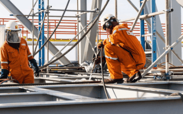Maintenance worker looks at the security of cables he is working on 