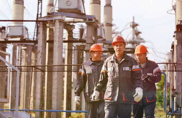 3 site managers walking through outdoor power facility