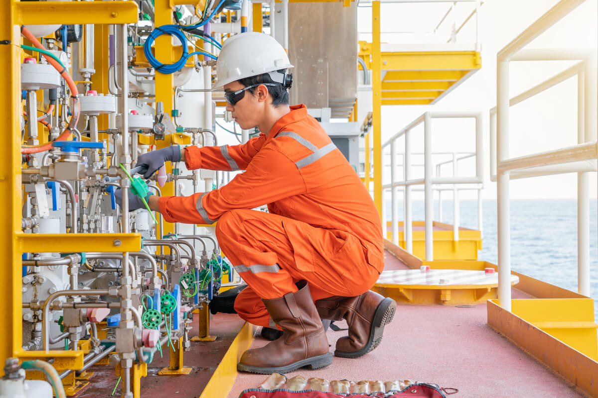 Maintenance technician in PPE inspecting valves and wires