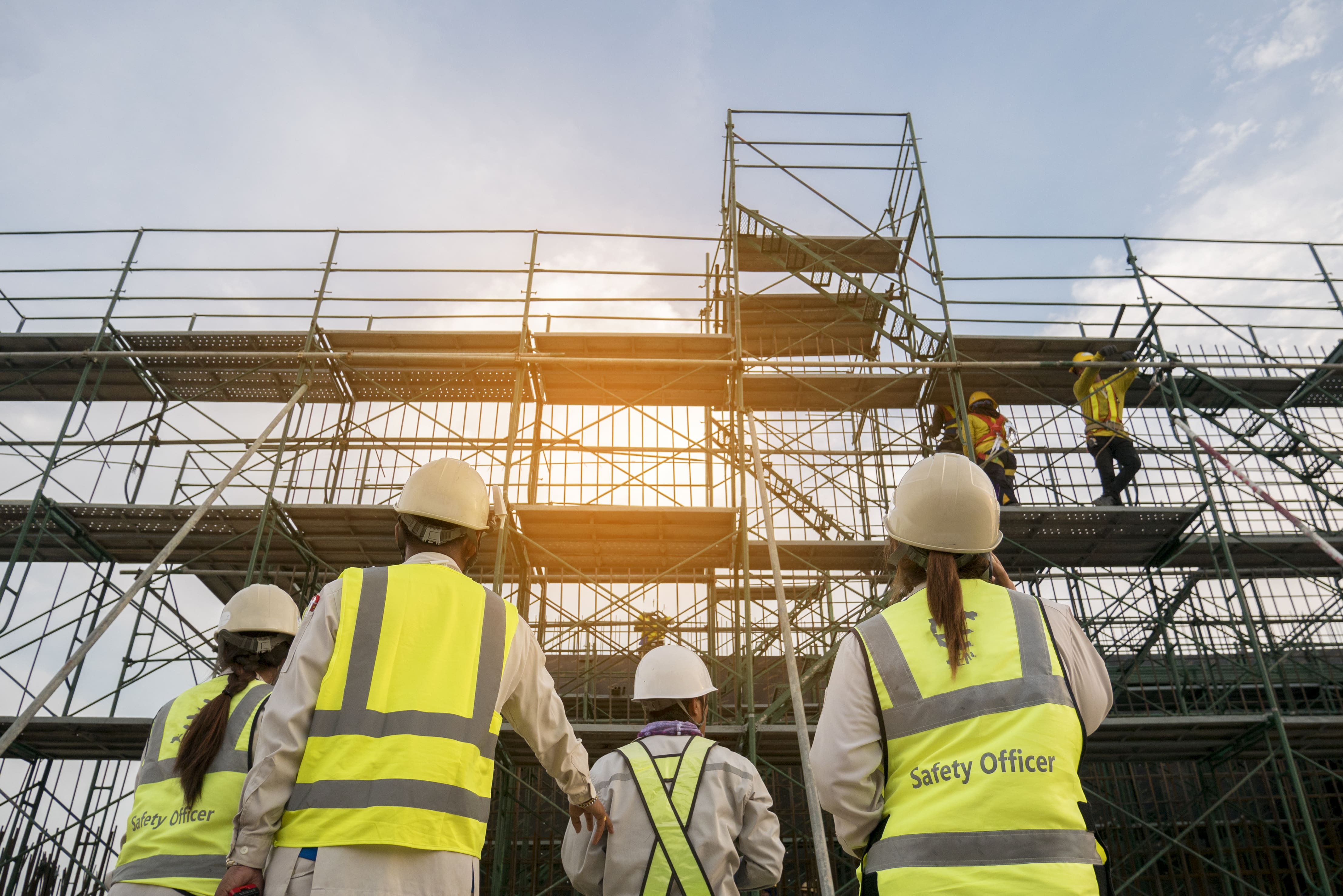 4 maintenance workers evaluating scaffolding while two technicians work