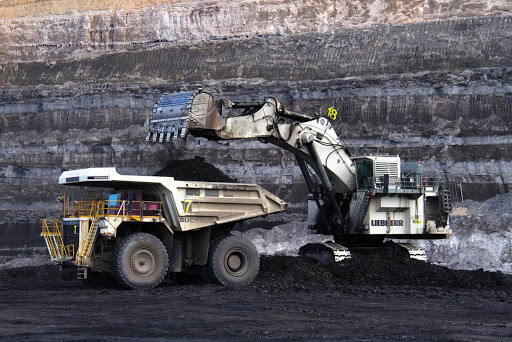 Backhoe pouring material into dump truck