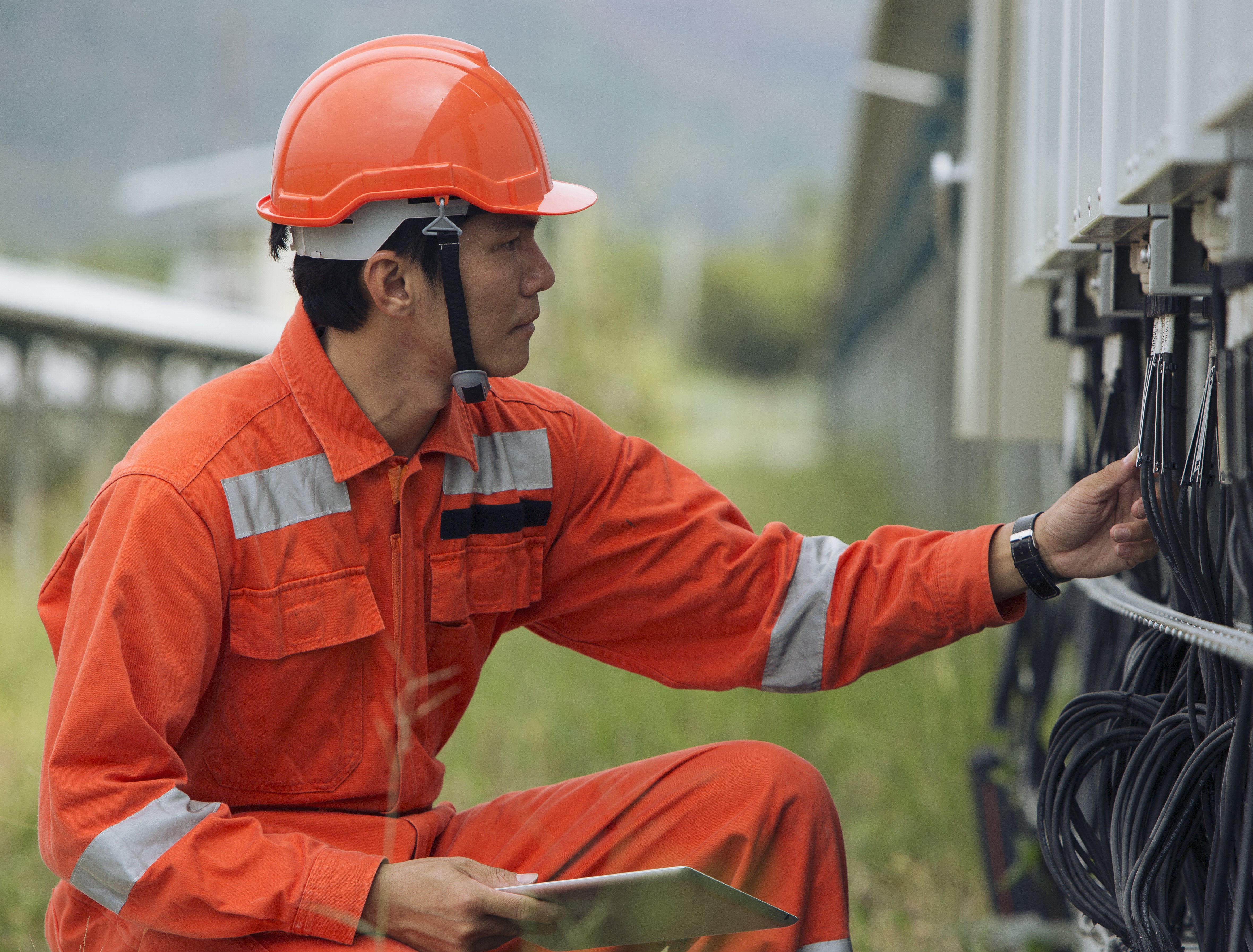 Maintenance technician checking wires on the exterior of a building